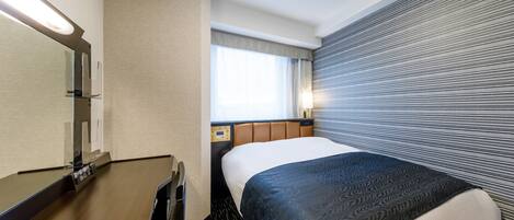 Habitación de hotel con una cama grande, una mesita de noche, un espejo y una ventana con cortinas.