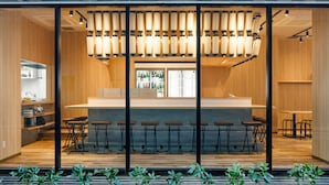 A modern bar area with a wooden interior, a glass partition, and a row of bar stools. - APA Hotel Hakata Gion Ekimae (Fukuoka)