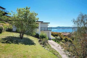 Ein modernes Haus mit einem Balkon mit Blick auf eine Küstenlandschaft.