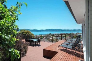 Eine Terrasse mit Tisch und Stühlen, eine Liegewiese und Meerblick.