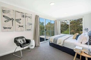 A bedroom with a bed, a chair, a bedside table, and artwork on the wall.