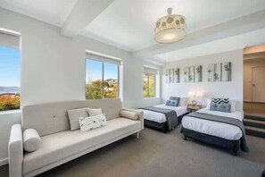 A hotel room with a sofa, two beds, a chandelier, and artwork on the walls. - House on the Hill with a View – Sleeps 12, 3 Bath. (Sandy Bay)