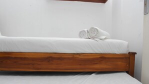 Una cama individual con estructura de madera y ropa de cama blanca.