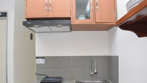 Una cocina con horno empotrado, lavamanos y armarios de madera.