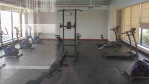 Een sportschool met trainingsapparatuur, grote ramen en een hoge nok.