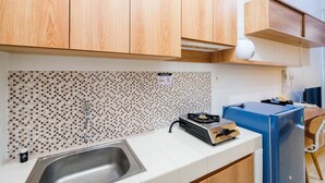 Een moderne keuken met houten kastjes, een betegelde spatwand, een spoelbak, een fornuis en een koelkast.