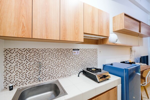 Una cocina moderna con armarios de madera, salpicadero de azulejos, un lavamanos, una estufa y un refrigerador.