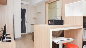 Une chambre d’hôtel moderne dotée d’un bureau en bois, d’un ordinateur portable, d’une télévision à écran plat, d’un petit coin salon et d’un mini-bar.