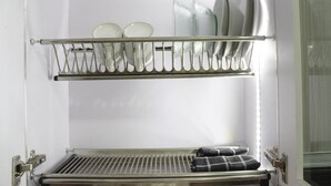 A kitchen with a dish rack holding plates and bowls, a sink, and a towel rack with folded towels. - Pleasurable Studio Room Near Unpad At Taman Melati Jatinangor Apartment (Hegarmanah)