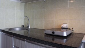 A kitchen with a stainless steel sink, a microwave, and a toaster on the countertop. - Pleasurable Studio Room Near Unpad At Taman Melati Jatinangor Apartment (Hegarmanah)