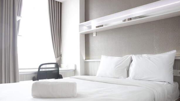 A hotel room with a neatly made bed, a chair, and a window with curtains. - Pleasurable Studio Room Near Unpad At Taman Melati Jatinangor Apartment (Hegarmanah)