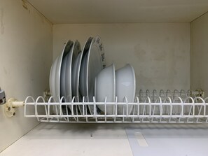 A dish rack with multiple plates and bowls inside a kitchen cabinet. - Cozy Studio Apartment With City View At Tamansari Sudirman (Jakarta)