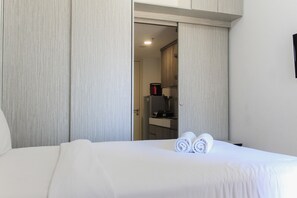 Une chambre d’hôtel avec un lit, une salle de bain visible à travers une porte ouverte et un petit coin cuisine.