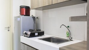 A kitchen with a refrigerator, a coffee maker, and a sink. - Comfy Studio Apartment At M-Town Residence (Gading Serpong)