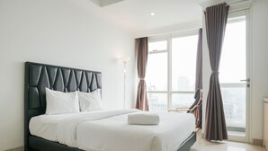 Ett modernt hotellrum med en stor säng, utsikt över staden och ett fönster med gardiner.