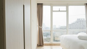 A hotel room with a large window, a bed, and a wardrobe.
