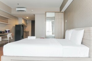 A hotel room with a bed, a desk, a refrigerator, and a mirror. - Comfortable And Nice Studio Room Apartement At H Residence (Jakarta)