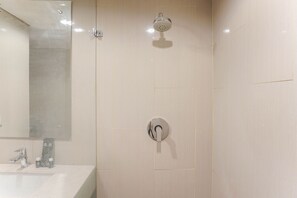 A modern bathroom with a large mirror, a sink, and a shower with a handheld showerhead. - Comfortable And Nice Studio Room Apartement At H Residence (Jakarta)