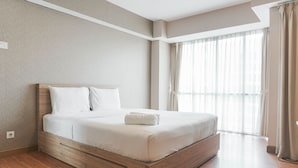 A neatly made bed with a wooden headboard, a window with sheer curtains, and a light-colored wall. - Comfortable And Nice Studio Room Apartement At H Residence (Jakarta)