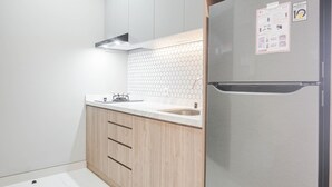 Eine moderne Küche mit einem Edelstahl-Kühlschrank, Holzschränken, einer weißen Arbeitsplatte und einer Rückwand mit sechseckigen Fliesen.