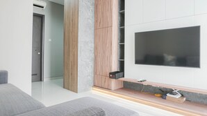 Ein modernes Wohnzimmer mit einem flachbildfernseher an der Wand, einer Wandpaneele aus Holz und einer eingebauten Ablage für elektronische Geräte.
