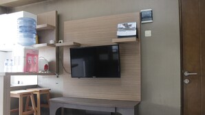 Ein modernes Zimmer mit einem an einer Holzwand befestigten Flachbildfernseher, einem kleinen Kalender und einem Wasserspender.
