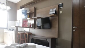 Ein Hotelzimmer mit Bett, Schreibtisch, Fernseher und Minibar.