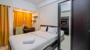A hotel room with a bed, a desk with a chair, a desk lamp, and a wardrobe. - Warm And Cozy Studio Apartment At Margonda Residence 5 (Depok)