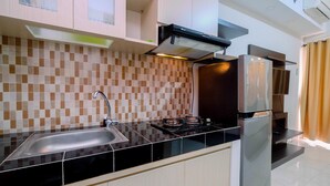 A modern kitchen with a black countertop, stainless steel sink, and a built-in stove. - Warm And Cozy Studio Apartment At Margonda Residence 5 (Depok)