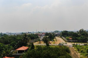 A residential area with a paved road, a small building with a red roof, and surrounding greenery. - Cozy Living Studio Room At Urbantown Serpong Apartment (South Tangerang)