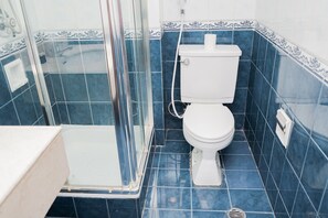 Compact bathroom with a modern design, featuring a white toilet and glass-enclosed shower area.