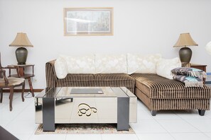 Relax in this stylish living room with a large L-shaped sofa, glass coffee table, and framed artwork.