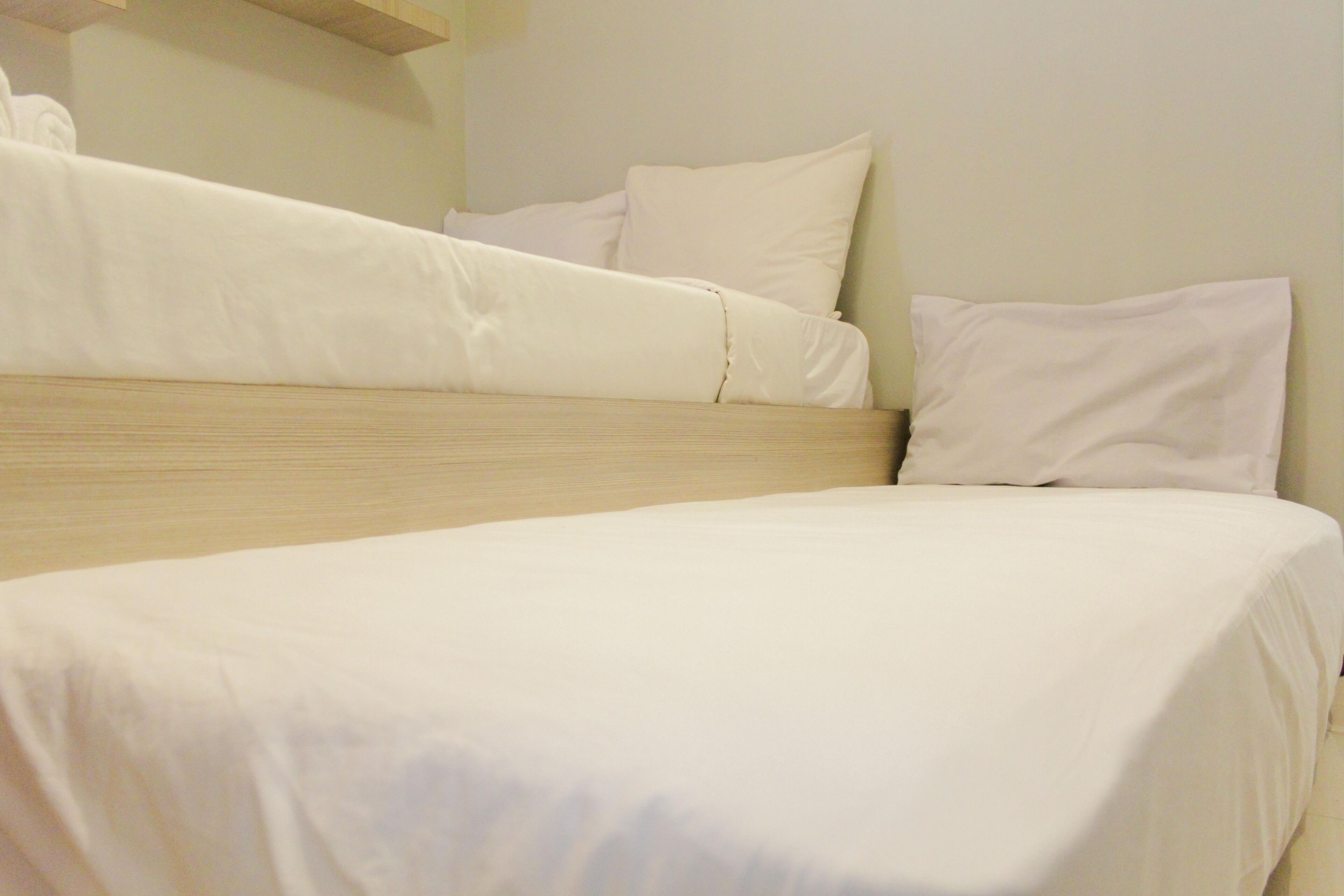 A single bed with a wooden headboard and white bedding.