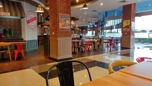 A restaurant interior with wooden tables and chairs, a brick column, and motivational quotes on the walls. - Fresh And Bright Studio Room At Nifarro Park Apartment (Jakarta)