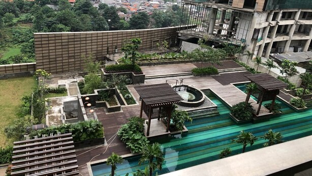 A rooftop garden with a swimming pool, seating areas, and a view of the cityscape.