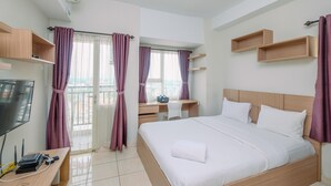 A hotel room with a bed, a desk, a TV, and a balcony with curtains. - Cozy Stay Studio Apartment At Margonda Residence 5 (Depok)