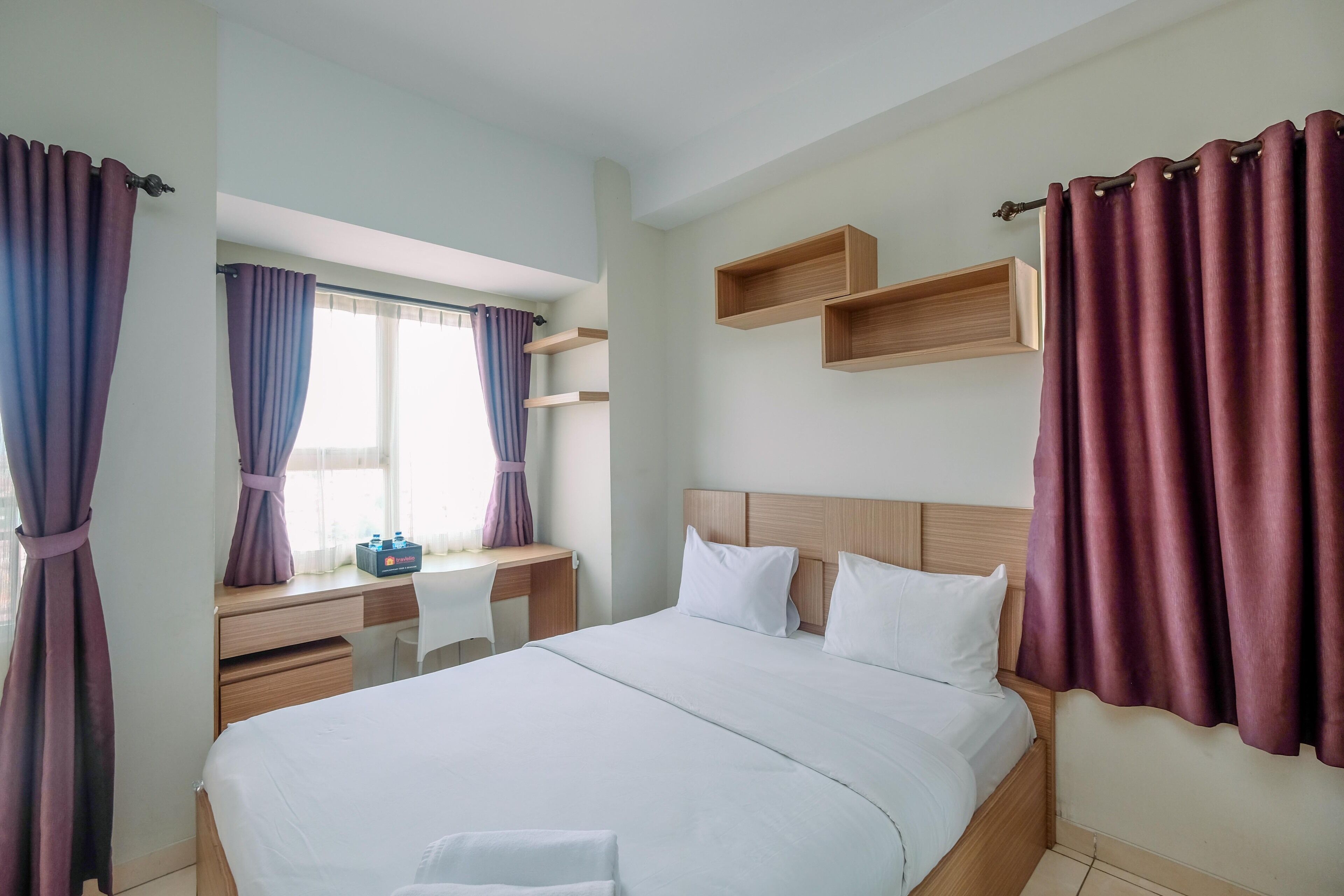 A hotel room with a bed, a desk, and a chair.