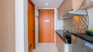 A narrow kitchen with wooden cabinets, a stainless steel sink, and a tiled backsplash. - Cozy Stay Studio Apartment At Margonda Residence 5 (Depok)