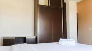 A hotel room with a large bed, a wooden wardrobe, and a door. - Comfy 2Br Apartment At Park View Condominium (Depok)