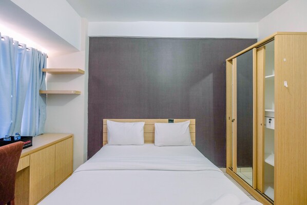 Ein Hotelzimmer mit einem Bett, einem Holzschrank, einem Schreibtisch und einem Vorhang.