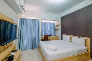 Ein Hotelzimmer mit Bett, Schreibtisch, Stuhl, Fernseher und einem Fenster mit Vorhängen.