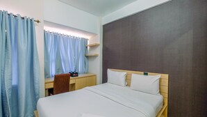 A hotel room with a bed, a desk, a chair, and a window with curtains. - Comfy And Modern Margonda Residence 5 Studio Apartment (Depok)