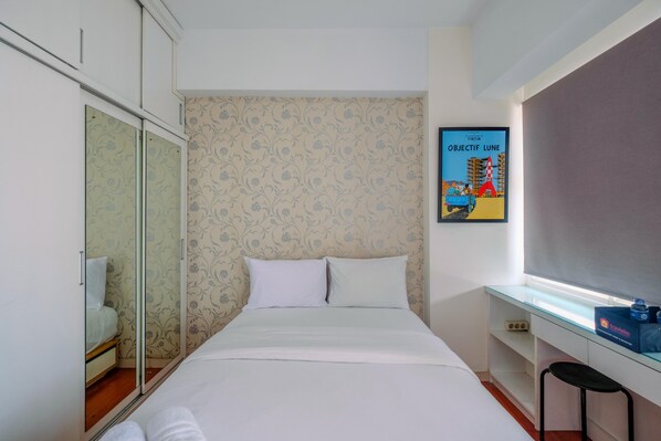 Ein Schlafzimmer mit einem Bett, einem Kleiderschrank, einem Schreibtisch und einem Bild an der Wand.