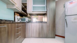 A kitchen with wooden cabinets, a microwave, a refrigerator, and a sink. - Spacious For 2Br Apartment At Sudirman Tower Condominium (Jakarta)