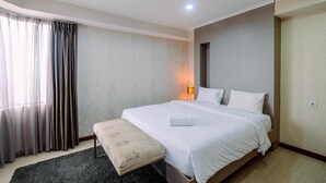 A hotel room with a bed, a bedside table, a lamp, and a window with curtains. - Spacious For 2Br Apartment At Sudirman Tower Condominium (Jakarta)