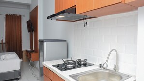 Una cucina compatta con fornello a gas, lavandino e pensili in legno.