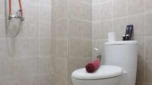 Une salle de bain équipée de toilettes, d’une douche et d’un porte-rouleau de papier toilette.