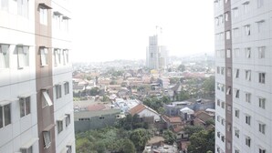 Un immeuble de grande hauteur, doté de nombreux étages et de nombreuses fenêtres, qui surplombe une zone urbaine densément peuplée, avec divers bâtiments et des espaces verts.