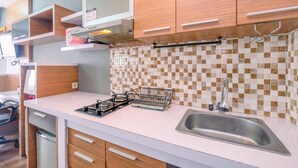 A modern kitchen with white countertops, wooden cabinets, a stainless steel sink, and a tiled backsplash. - Cozy Stay Studio Apartment At Park View Condominium (Depok)
