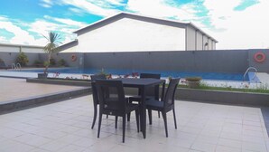 An outdoor patio with a pool, a covered seating area, and a building with a white facade. - Cozy Stay Studio Apartment At Park View Condominium (Depok)
